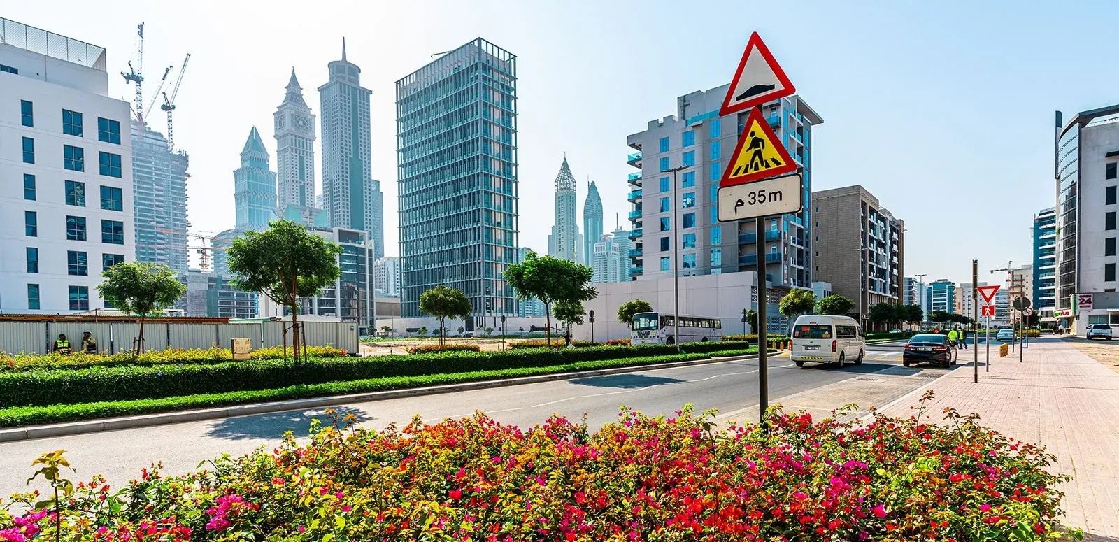Street-level view across Jumeirah Garden City toward the Dubai skyline